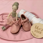 Tan soft leather baby moccasins featuring bow and fringe trim
